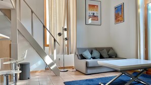 Ein modernes Wohnzimmer mit Sofa, Esstisch, Stuhl, Treppe und einem großen Fenster mit Vorhängen.