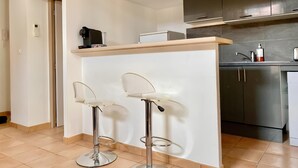 Eine moderne Küche mit Barbereich, Edelstahlgeräten und zwei Barhocker.