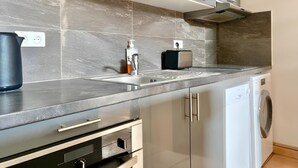 Eine moderne Küche mit eingebautem Backofen, Spüle und Geschirrspüler.