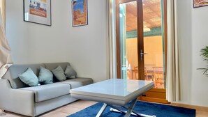 Ein Wohnzimmer mit einer Couch, einem Couchtisch und einer Glastür, die zu einem Außenbereich führt.
