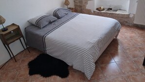 Un dormitorio con cama, mesita de noche, lámpara y ventana.