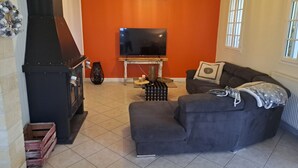 Una sala de estar con chimenea, sofá, televisor y ventana.