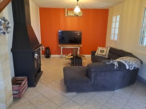 A living room with a fireplace, a sofa, a television, and a window.