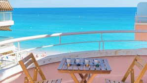 Un balcon avec une table et des chaises donnant sur une plage.