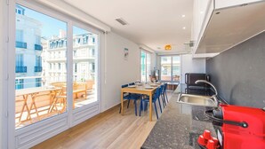 Une cuisine moderne avec un coin repas, de grandes fenêtres et une vue sur les immeubles.