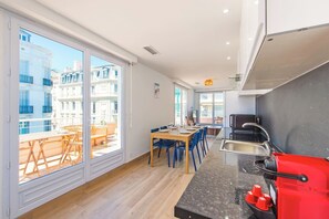 Una cucina moderna con zona pranzo, ampie finestre e vista sugli edifici.