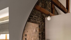 Un dormitorio con cama, lámpara y pared de piedra.
