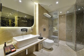 A modern bathroom with a large bathtub, a toilet, and a glass-enclosed shower area. - Ginger Ajmer Hathi Bhata (Ajmer)