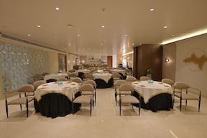 A spacious banquet hall with multiple round tables, each with a white tablecloth and black drapery, arranged in rows. - Ginger Ajmer Hathi Bhata (Ajmer)