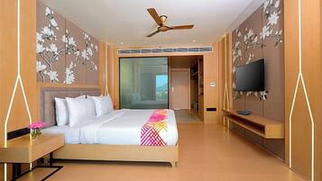 Una habitación de hotel con una cama, televisión, escritorio y un ventanal grande.