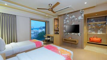 Habitación de hotel con dos camas, un escritorio, un televisor y vistas a la ciudad.