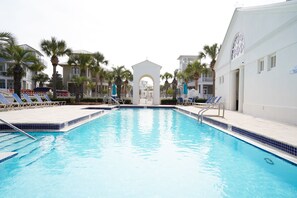 Una piscina con sillones de playa y palmeras.
