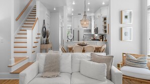 A modern interior with a staircase, a dining area, and a living room with a sofa and a wicker chair. - GemStone Cottage! Special Deals! Private Beach, Lux Home w/Free Bch Service! (Panama City Beach)