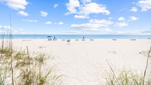 A beach with white sand, a clear blue sky, and a few beach umbrellas. - GemStone Cottage! Special Deals! Private Beach, Lux Home w/Free Bch Service! (Panama City Beach)