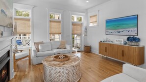 A spacious living room with a white sofa, a round coffee table, and a wooden cabinet. - GemStone Cottage! Special Deals! Private Beach, Lux Home w/Free Bch Service! (Panama City Beach)