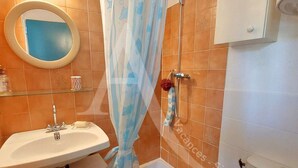 A bathroom with a sink, mirror, shower, and tiled walls. - Studio 2 personnes en rdc quartier de la Corniche (Sète)