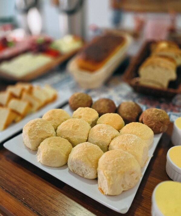 A table with various food items including pastries and bread. - Pousada Rio do Prado (Porto Seguro)