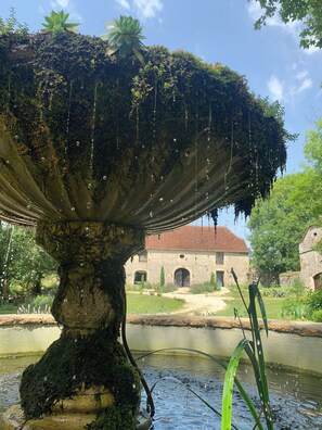 Water cascades from a traditional fountain in a serene garden setting.