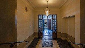 A hallway with a stone-tiled floor, a hanging light fixture, and a view into a room with a patterned rug. - CAMPO DE' FIORI PINKY HOUSE (Rome)