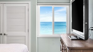 A bedroom with a large window offering a view of the ocean, a bed, a dresser, and a television. - 723- Beautiful, TOP FLOOR UNIT w/ Stunning Views! Free Beach Service (Destin)