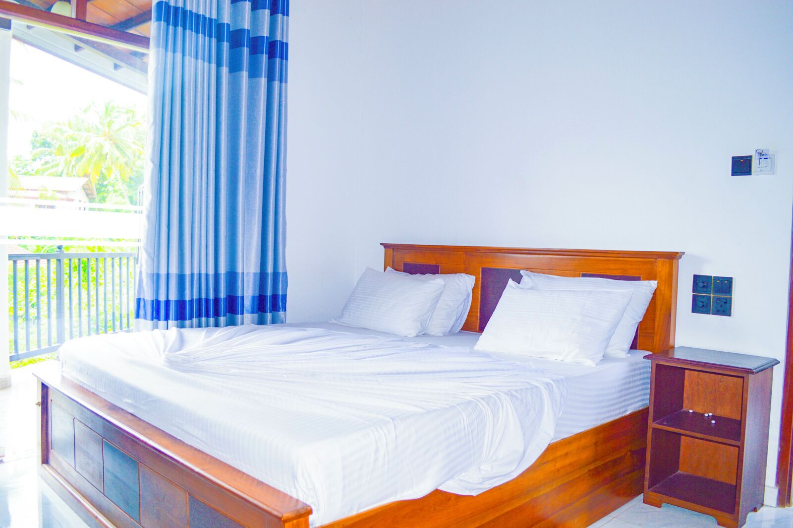 Una cama bien hecha con sábanas blancas en una habitación con cabecera de madera.