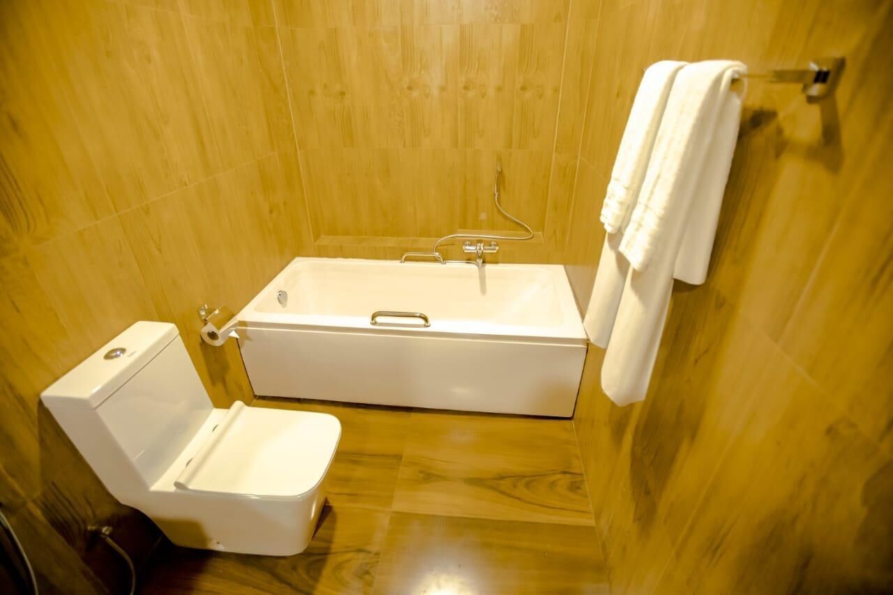 A bathroom with a bathtub, toilet, and towel rack.