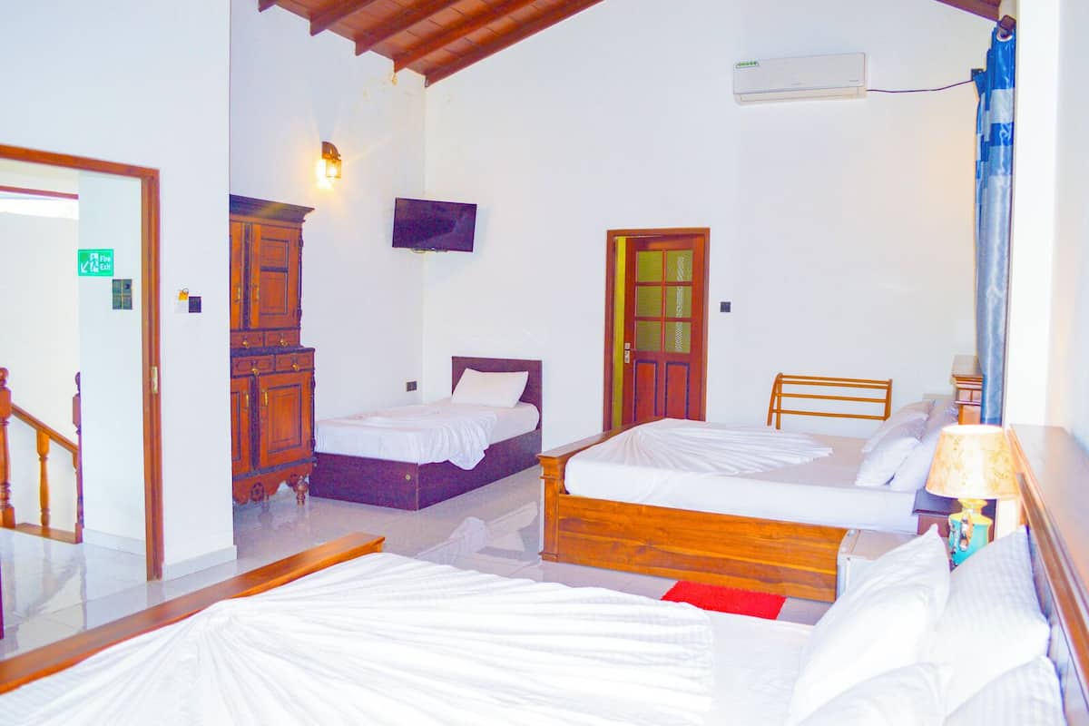 Une chambre d’hôtel avec deux lits, une armoire en bois, un téléviseur et une porte de salle de bain.