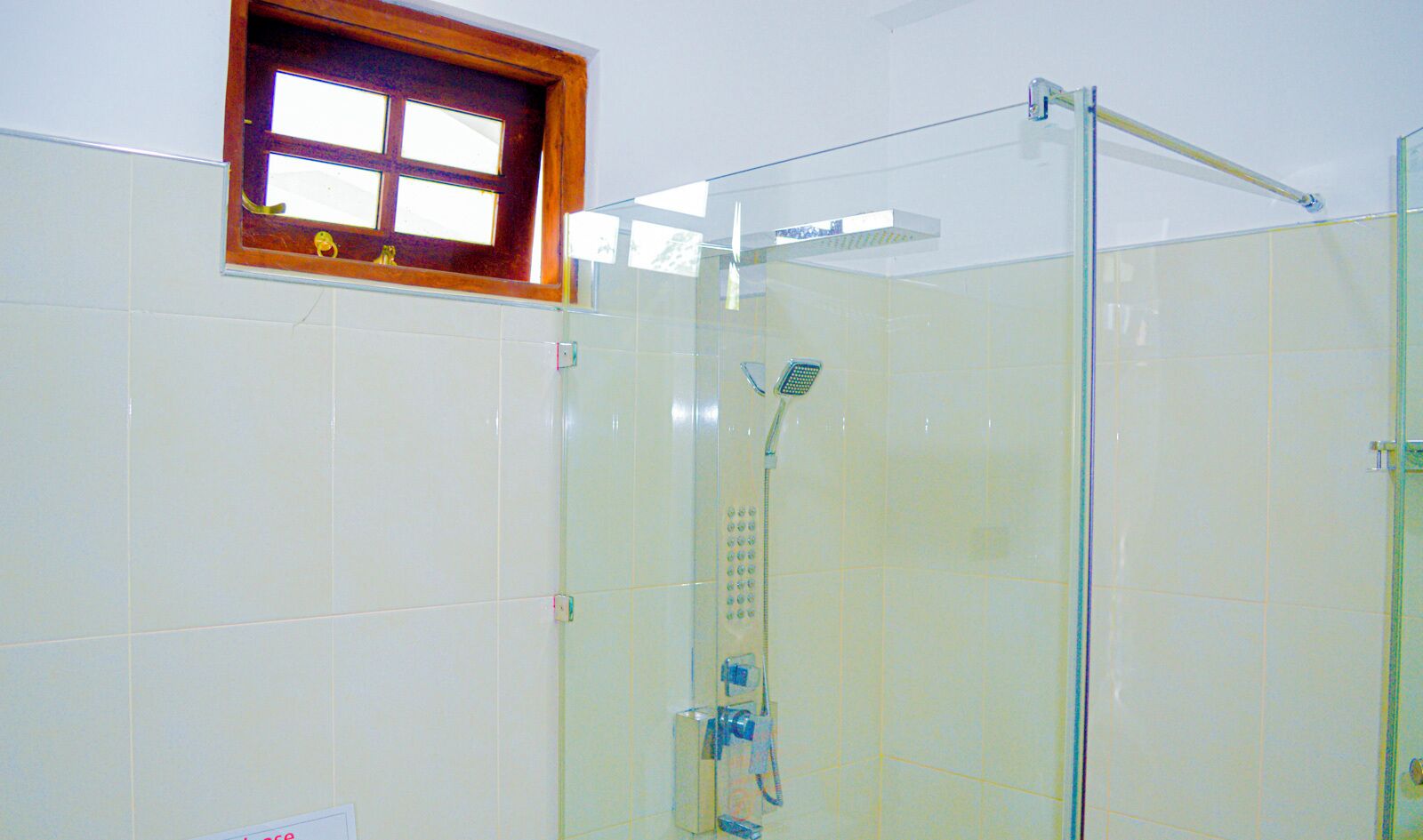 Une douche fermée par des parois en verre, dotée d’un pommeau de douche à main et d’un robinet mural.