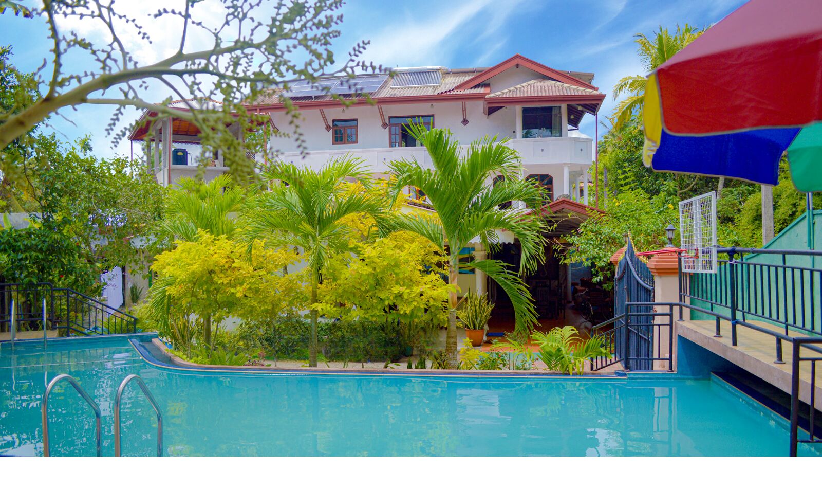 A pool area with a clear view of a building with a red roof and multiple windows.