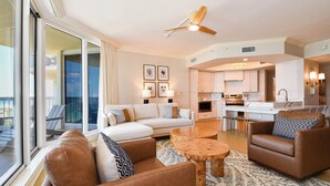 A spacious living area with a sofa, armchairs, and a coffee table. A kitchen is visible in the background. - Stunning beachfront condo w/ relaxing amenities in the heart of Destin! 🐚🏖🐟 (Destin)