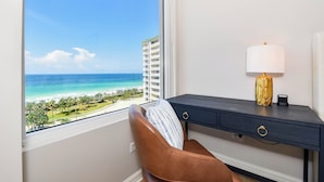 A room with a view of a beach and ocean, a desk with a lamp, and a chair. - Stunning beachfront condo w/ relaxing amenities in the heart of Destin! 🐚🏖🐟 (Destin)