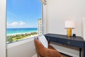 A room with a view of a beach and ocean, a desk with a lamp, and a chair. - Stunning beachfront condo w/ relaxing amenities in the heart of Destin! 🐚🏖🐟 (Destin)