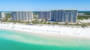 A beachfront hotel with multiple high-rise buildings, a sandy beach, and clear turquoise waters. - Stunning beachfront condo w/ relaxing amenities in the heart of Destin! 🐚🏖🐟 (Destin)