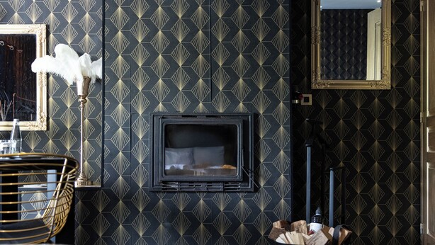 Une chambre d’hôtel moderne dotée d’un grand lit, d’une cheminée, d’un téléviseur fixé au mur et d’un miroir décoratif.