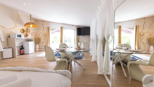A modern hotel room with a glass dining table, white furniture, and a large mirror. - Hacienda d'Amore (Oletta)