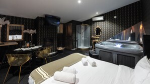 A hotel room with a bed, a desk with a chair, a shower area, and a jacuzzi. - Hacienda d'Amore (Oletta)