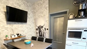 Eine moderne Küche mit Mikrowelle, Kaffeemaschine und einer Uhr an der Wand.