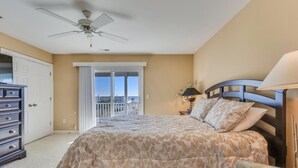 Un dormitorio con cama, cómoda, mesita de noche, lámpara y ventilador de techo.