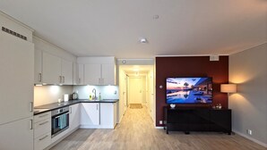 A modern apartment with a kitchen, living area, and a TV mounted on the wall.