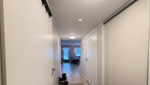 A hallway with a shoe rack, a dining area with a table and chairs, and a door with a light switch.