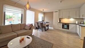A modern living room with a sofa, a coffee table, and a dining area with chairs and a table.