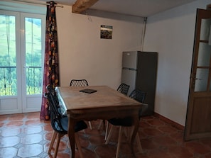 Ein Essbereich mit Tisch, Stühlen, einem Kühlschrank und Blick durch eine Tür.