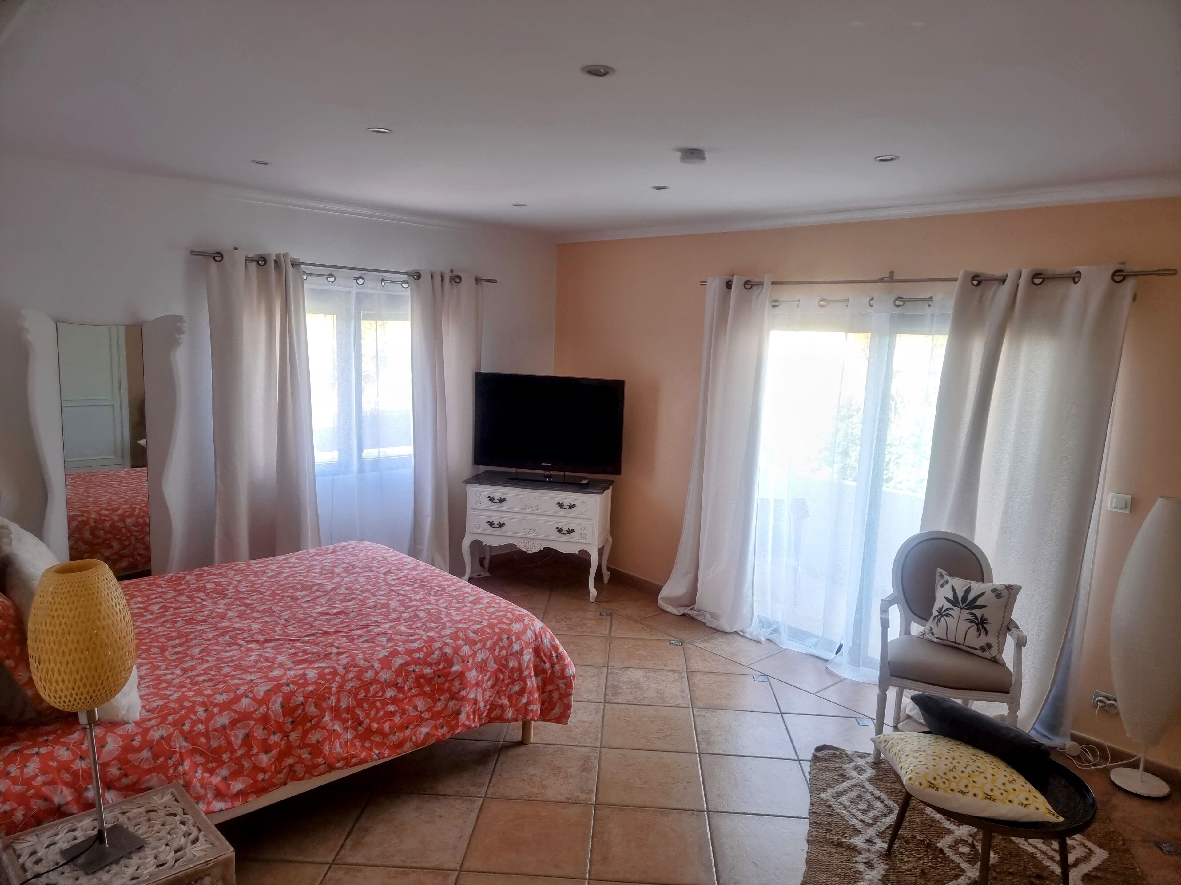 Un dormitorio con cama, televisión, silla y escritorio.