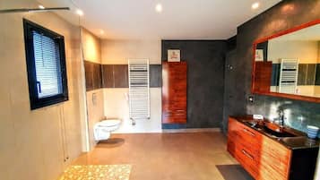 A modern bathroom with a large mirror, wooden vanity, and a tiled floor.