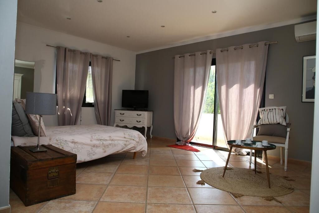 A bedroom with a bed, dresser, television, and a small table with chairs.