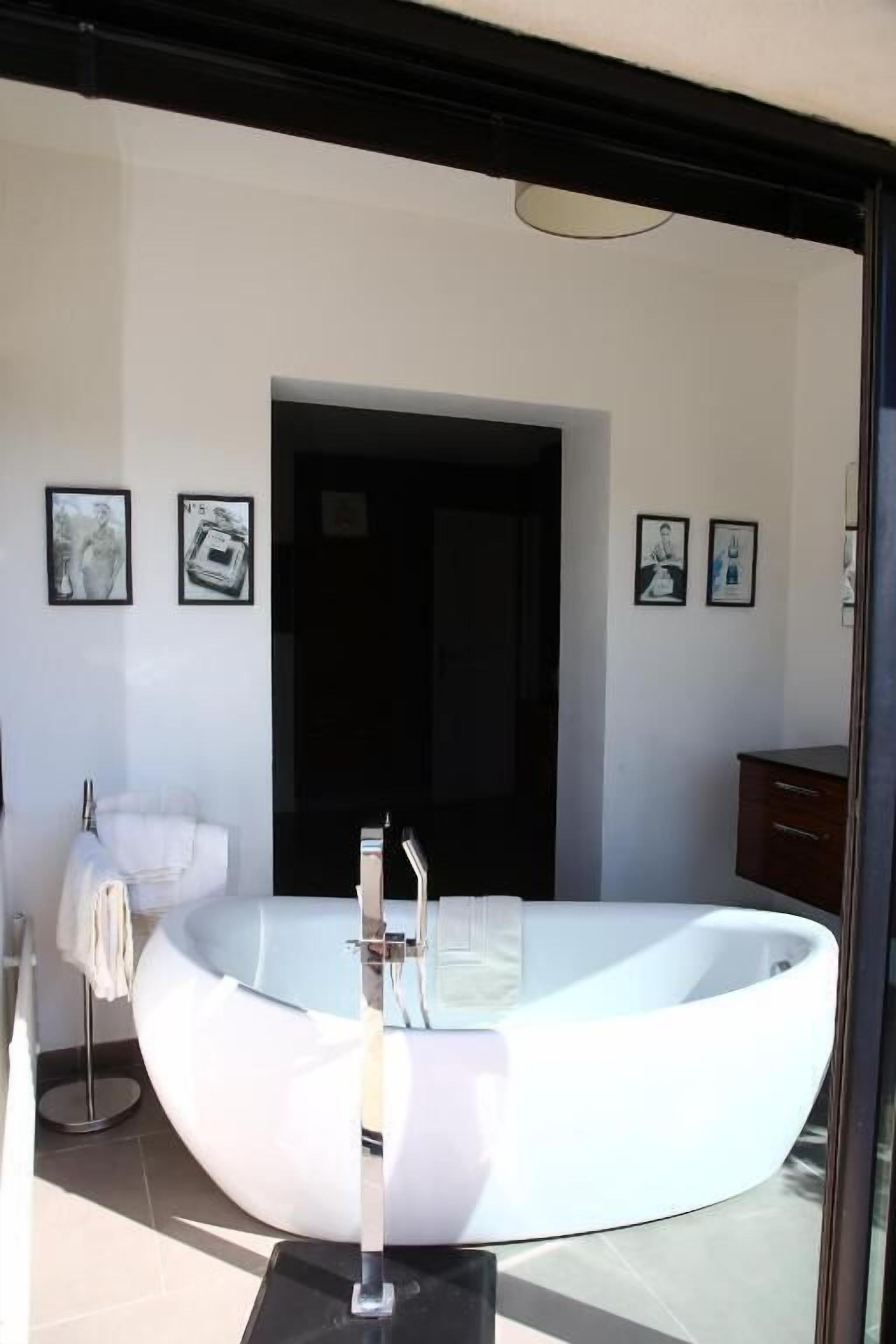 A modern bathroom with a freestanding bathtub, a large mirror, and a dark-toned cabinet.