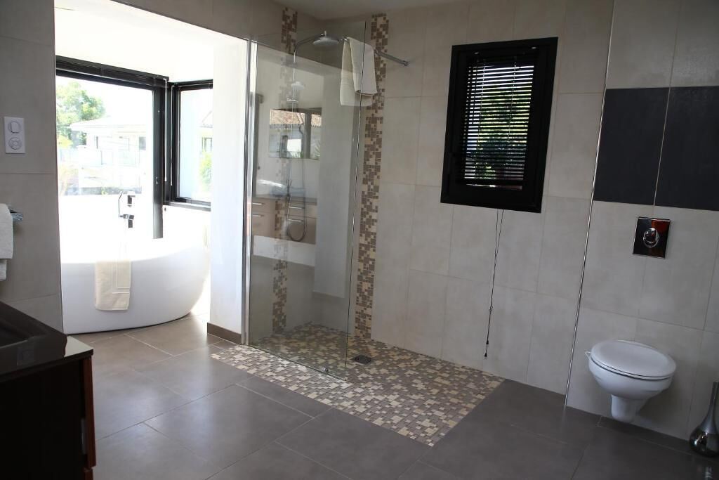 A modern bathroom with a glass-enclosed shower, a bathtub, and a toilet.