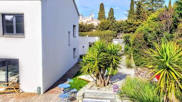 Une maison moderne dotée d’une piscine, entourée de différentes plantes et arbres.