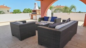 Un espace extérieur aménagé en terrasse, avec des meubles en osier, un barbecue et une vue sur le quartier environnant.