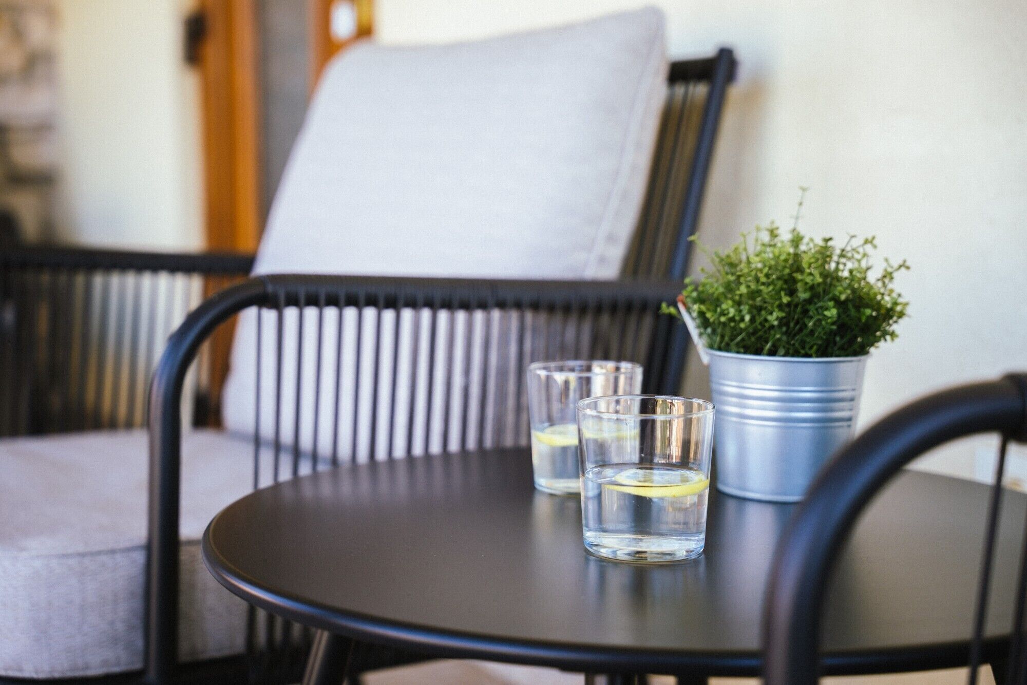 A round table with two glasses of water and a small potted plant.